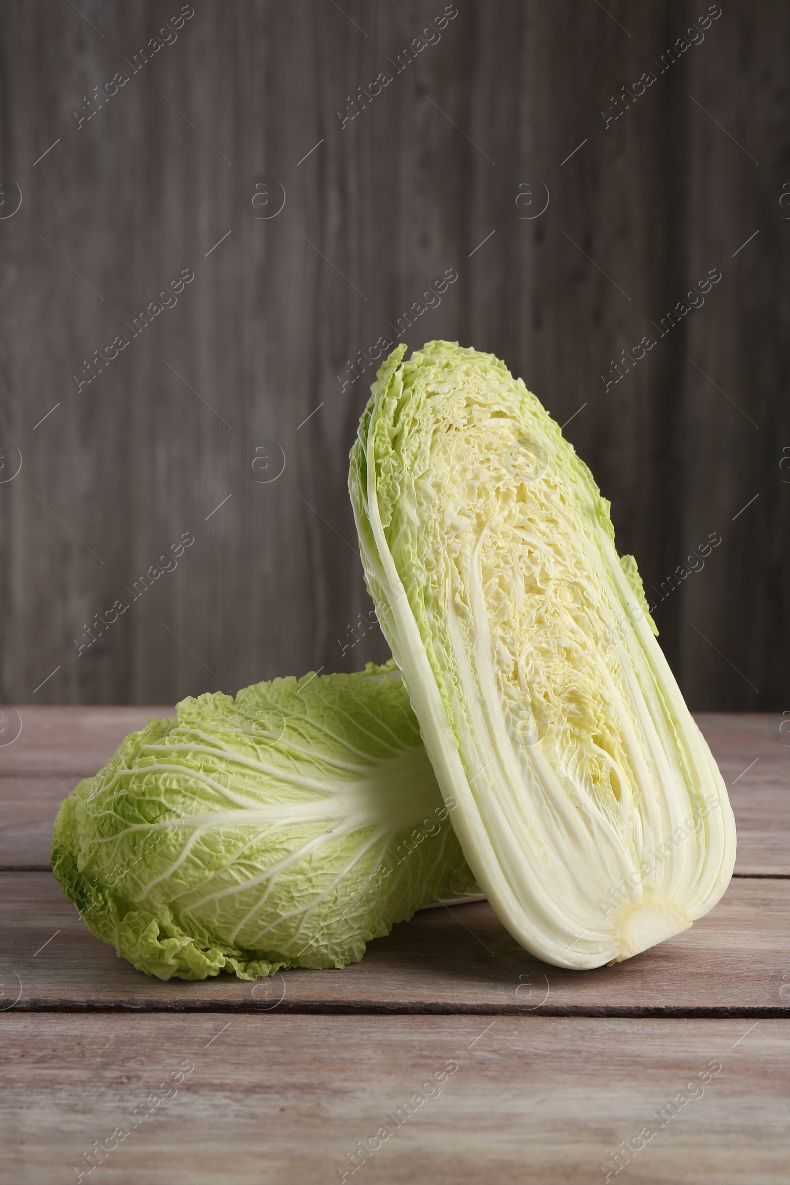 Photo of Whole and cut fresh ripe Chinese cabbages on wooden table