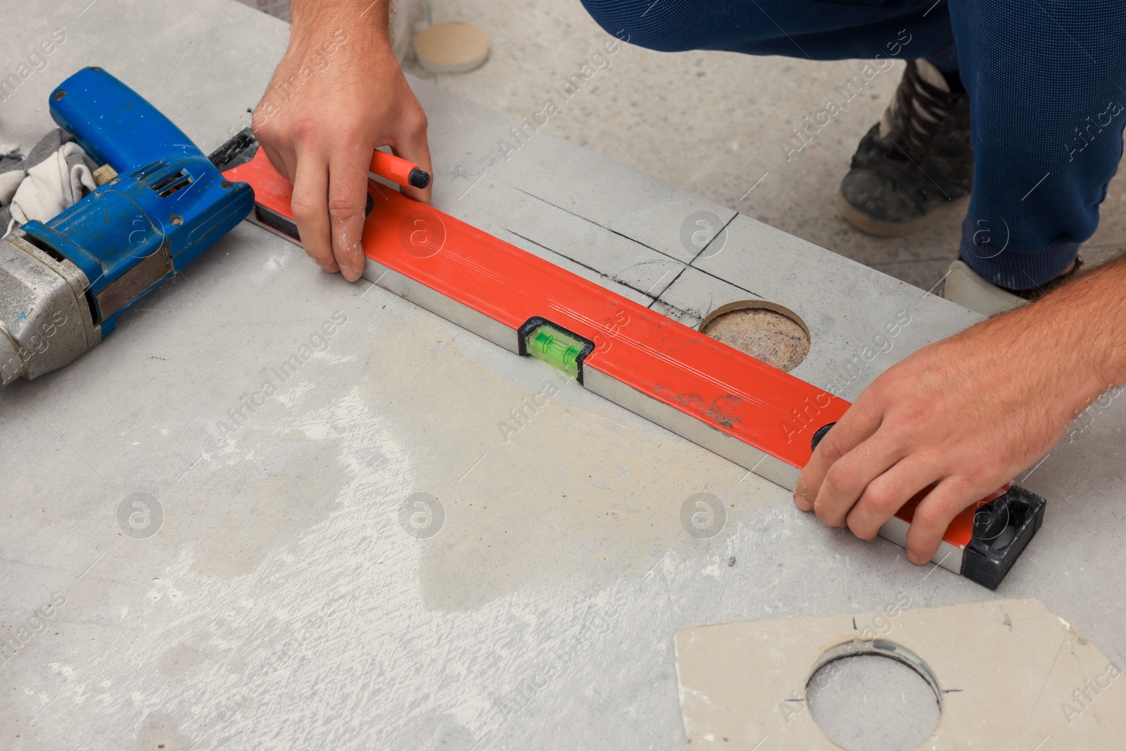 Photo of Worker making socket hole in tile indoors, closeup