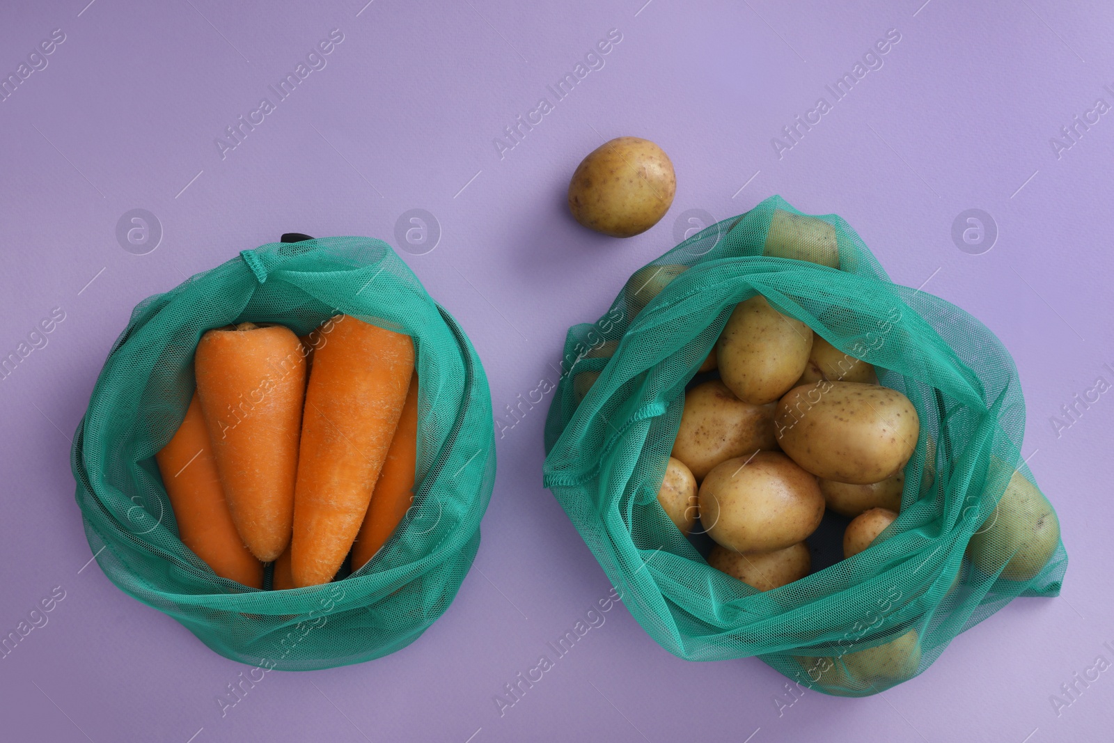 Photo of Net bags with vegetables on lilac background, top view