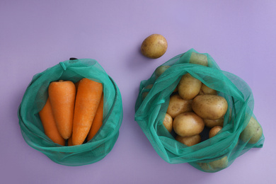 Photo of Net bags with vegetables on lilac background, top view