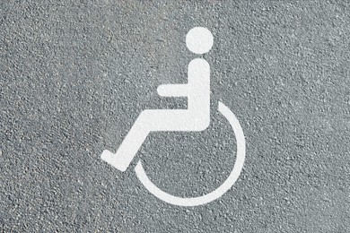 Wheelchair symbol on asphalt road, top view. Disabled parking permit