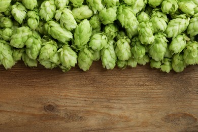 Photo of Fresh green hops on wooden table, top view. Space for text