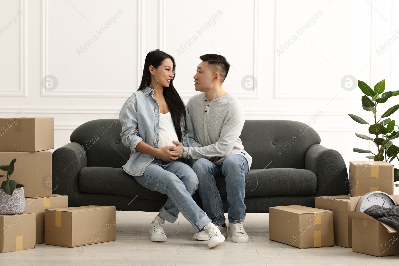 Photo of Pregnant woman and her husband on sofa in their new apartment