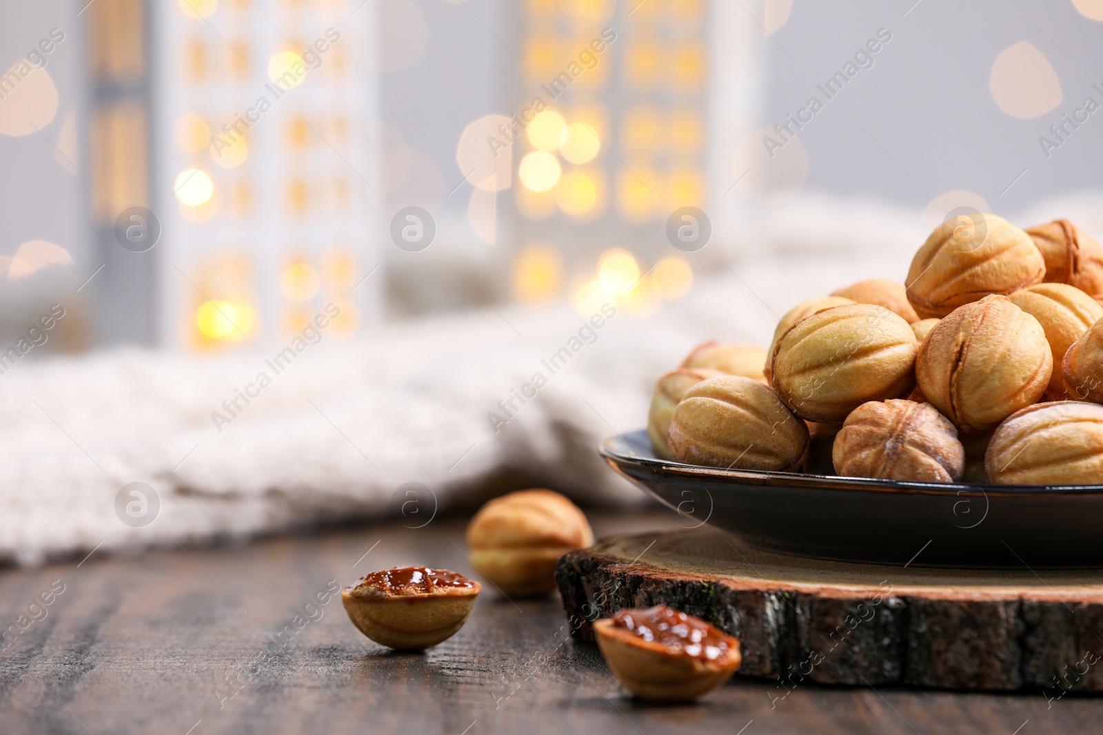 Photo of Homemade walnut shaped cookies with boiled condensed milk on wooden table, space for text. Bokeh effect