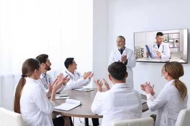 Image of Lecture with online participant. Doctors in meeting room. Using tv for videoconference