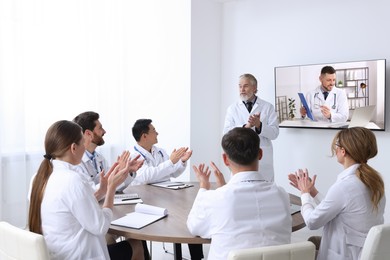 Lecture with online participant. Doctors in meeting room. Using tv for videoconference