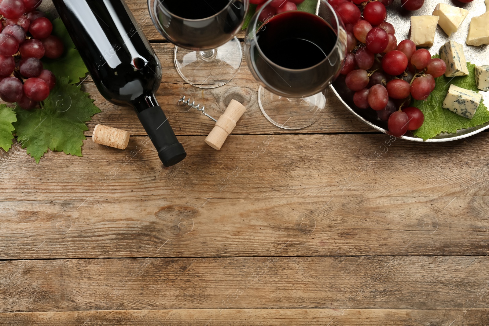 Photo of Tasty red wine and snacks on wooden table, flat lay. Space for text