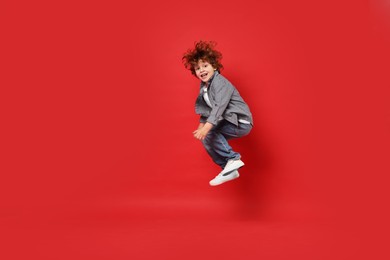 Happy little boy dancing on red background. Space for text