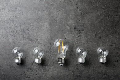 Vintage and modern lamp bulbs on grey stone surface. Space for text