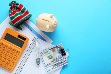 Photo of Flat lay composition with piggy bank and calculator on light blue background, space for text. Paying bills concept