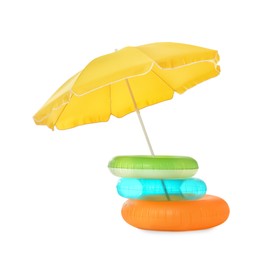 Open yellow beach umbrella with different inflatable rings on white background
