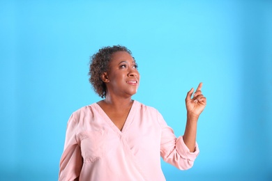 Portrait of happy African-American woman on light blue background