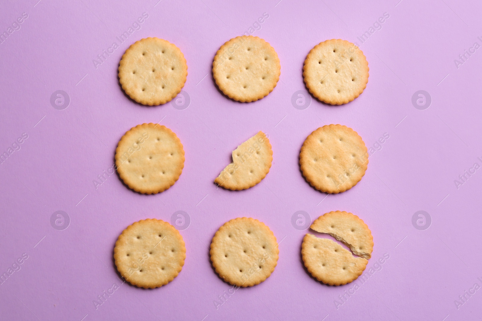 Photo of Delicious crackers on violet background, flat lay