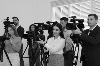 Image of Professional journalists with cameras indoors. Black and white effect