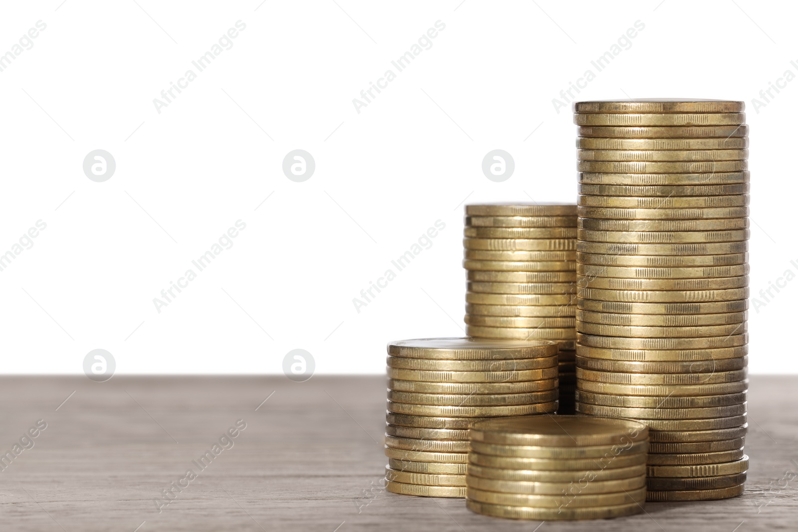 Photo of Many golden coins stacked on wooden table against white background, space for text