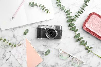 Flat lay composition with camera for professional photographer and accessories on white marble table