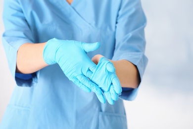 Doctor taking off medical gloves on color background