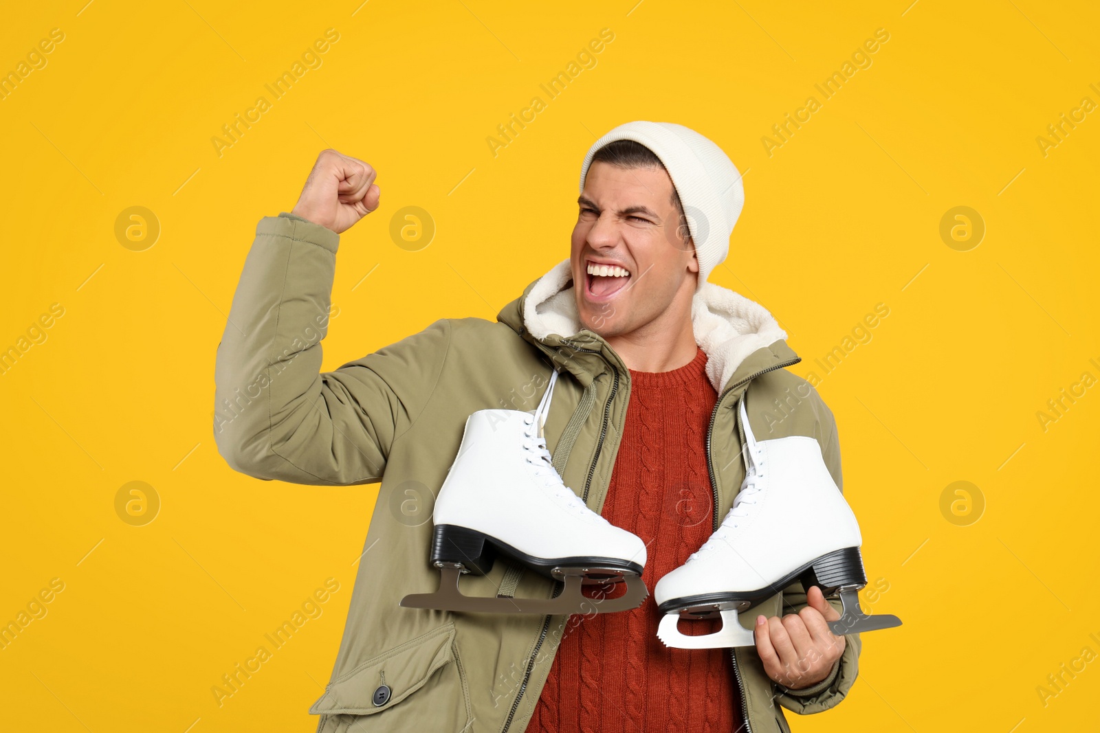 Photo of Emotional man with ice skates on yellow background