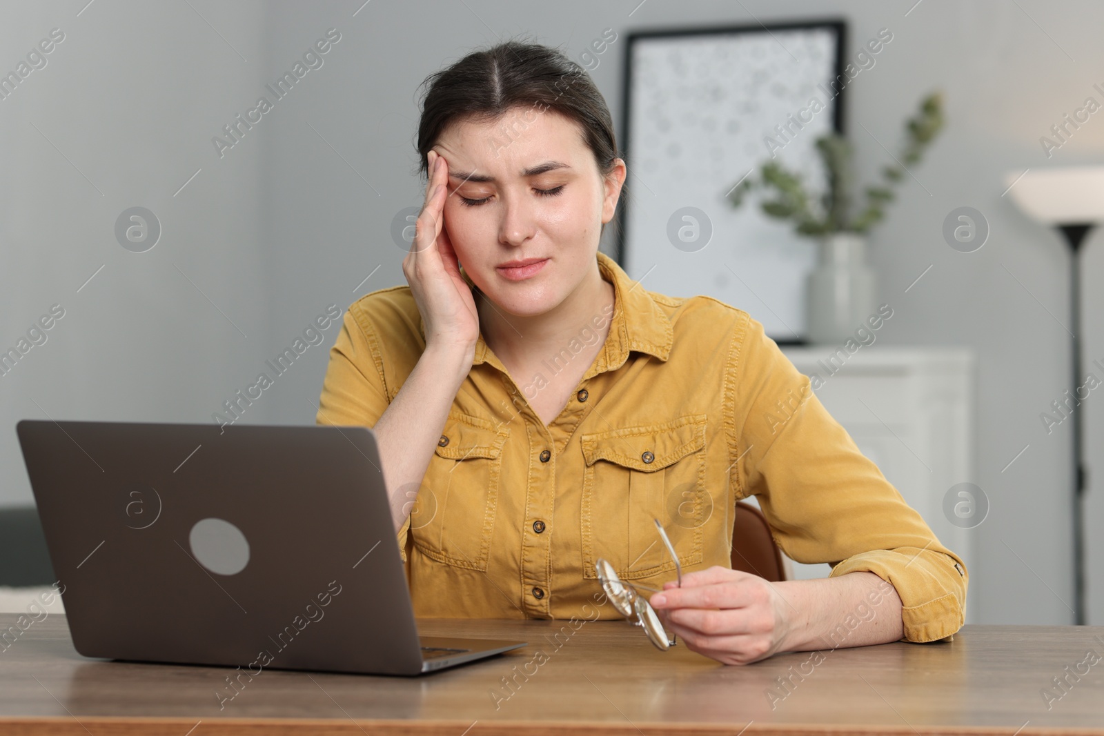 Photo of Overwhelmed woman sitting with laptop at table indoors