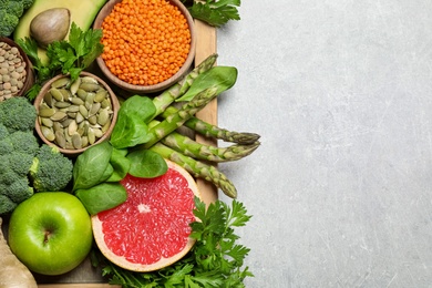 Photo of Fresh vegetables, fruits and seeds on grey table, flat lay. Space for text