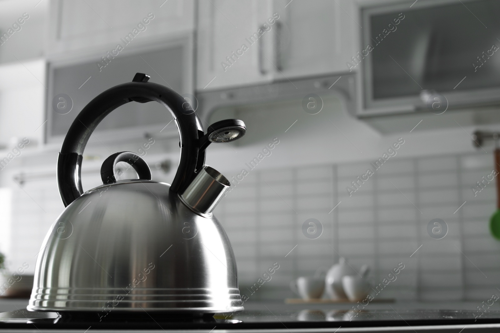 Photo of Modern kettle with whistle on stove in kitchen, space for text