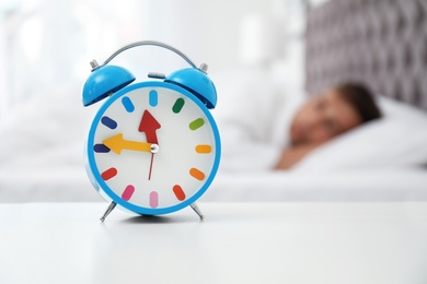 Analog alarm clock and blurred man on background. Time of day