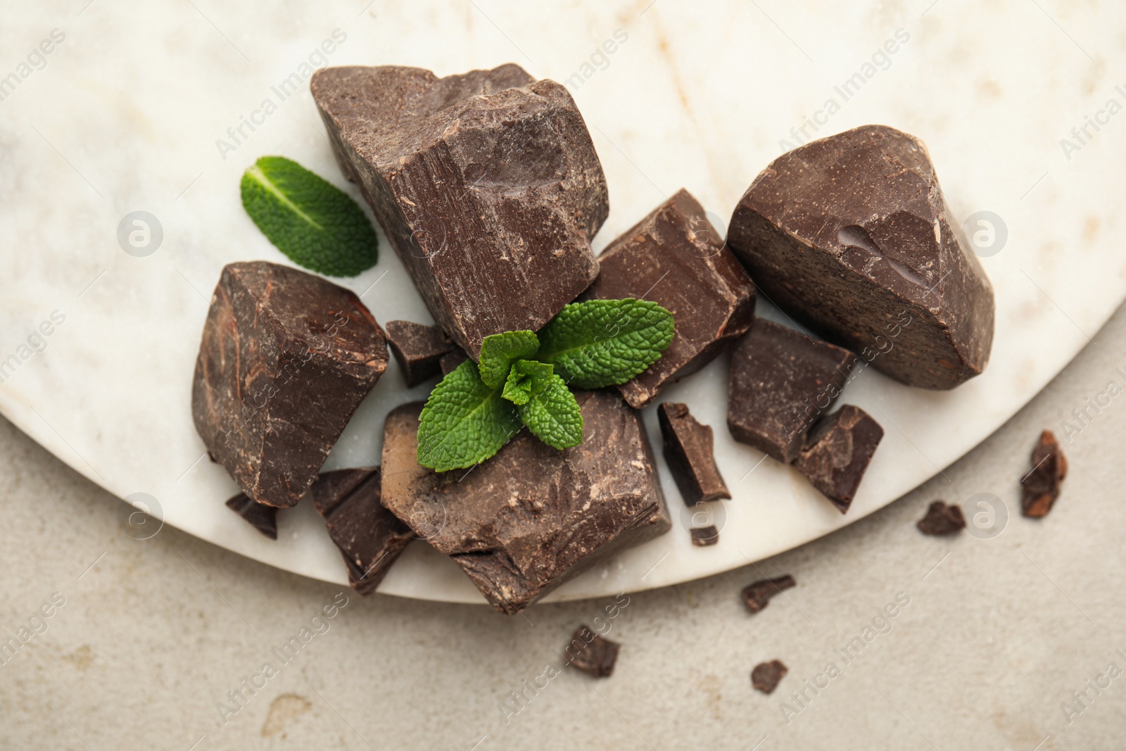 Photo of Tasty dark chocolate pieces with mint on white table, flat lay