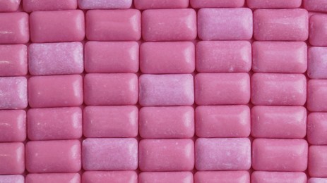 Photo of Many pink chewing gums as background, top view