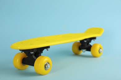 Photo of Yellow skateboard on light blue background, closeup. Sport equipment