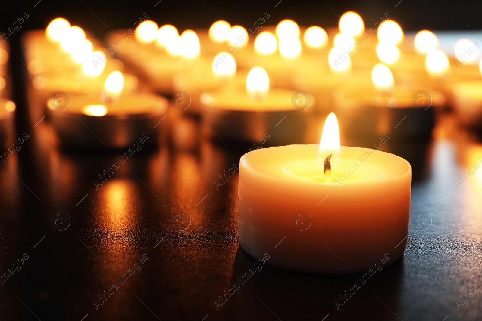 Photo of Wax candle burning on table in darkness, closeup