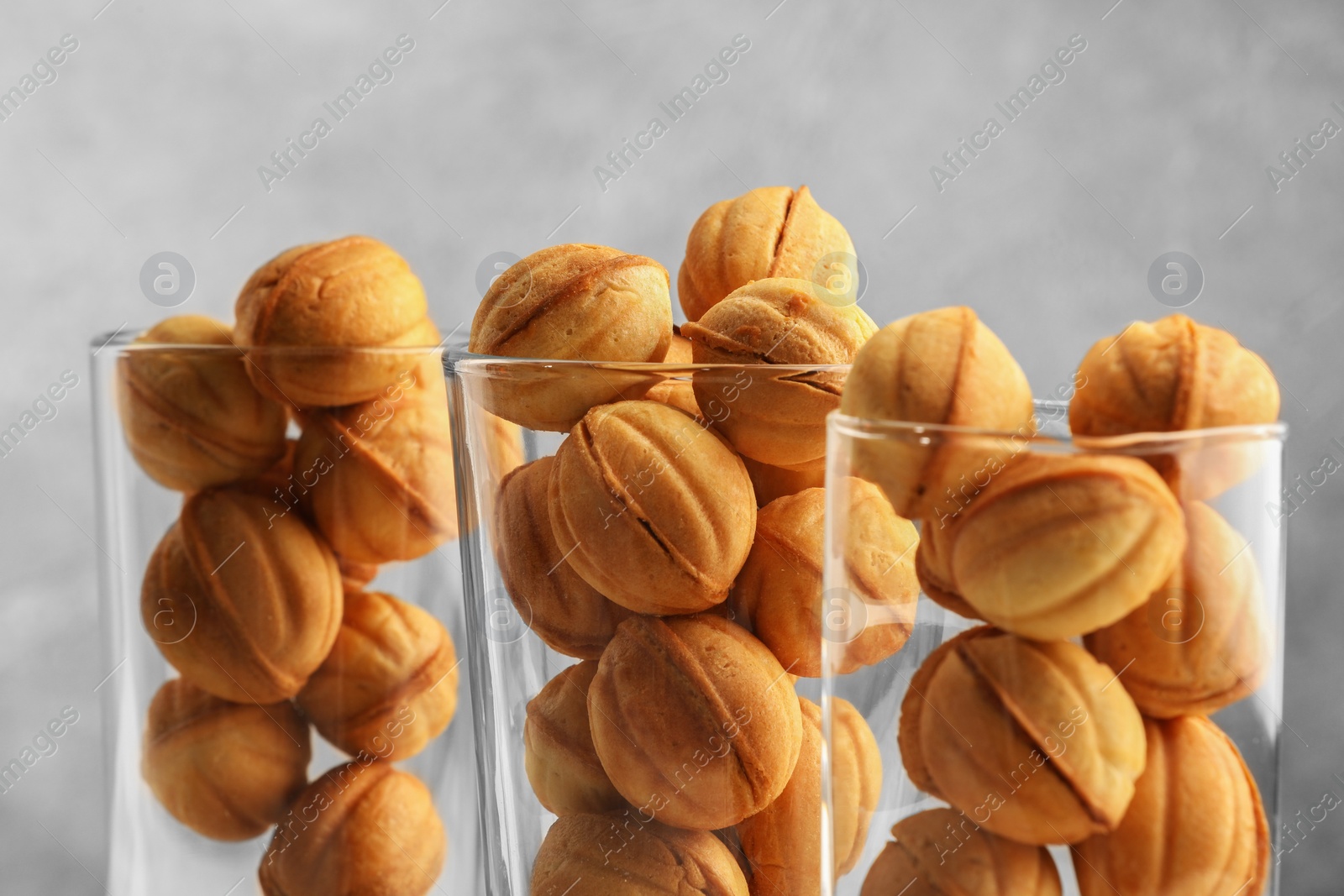 Photo of Tasty walnut shaped cookies served in glasses for welcoming guests on blurred background, closeup. Homemade pastry with caramelized condensed milk filling