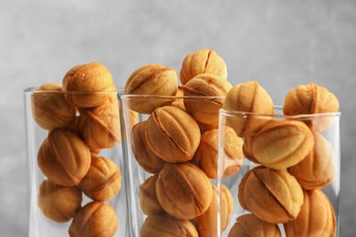 Photo of Tasty walnut shaped cookies served in glasses for welcoming guests on blurred background, closeup. Homemade pastry with caramelized condensed milk filling