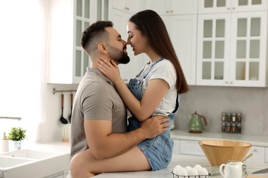 Photo of Affectionate young couple kissing in light kitchen