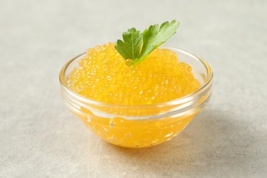 Fresh pike caviar in bowl and parsley on light grey table