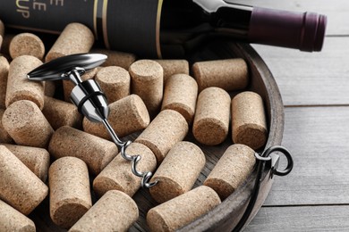 Photo of Tray with corkscrew, wine bottle and stoppers on wooden table, closeup