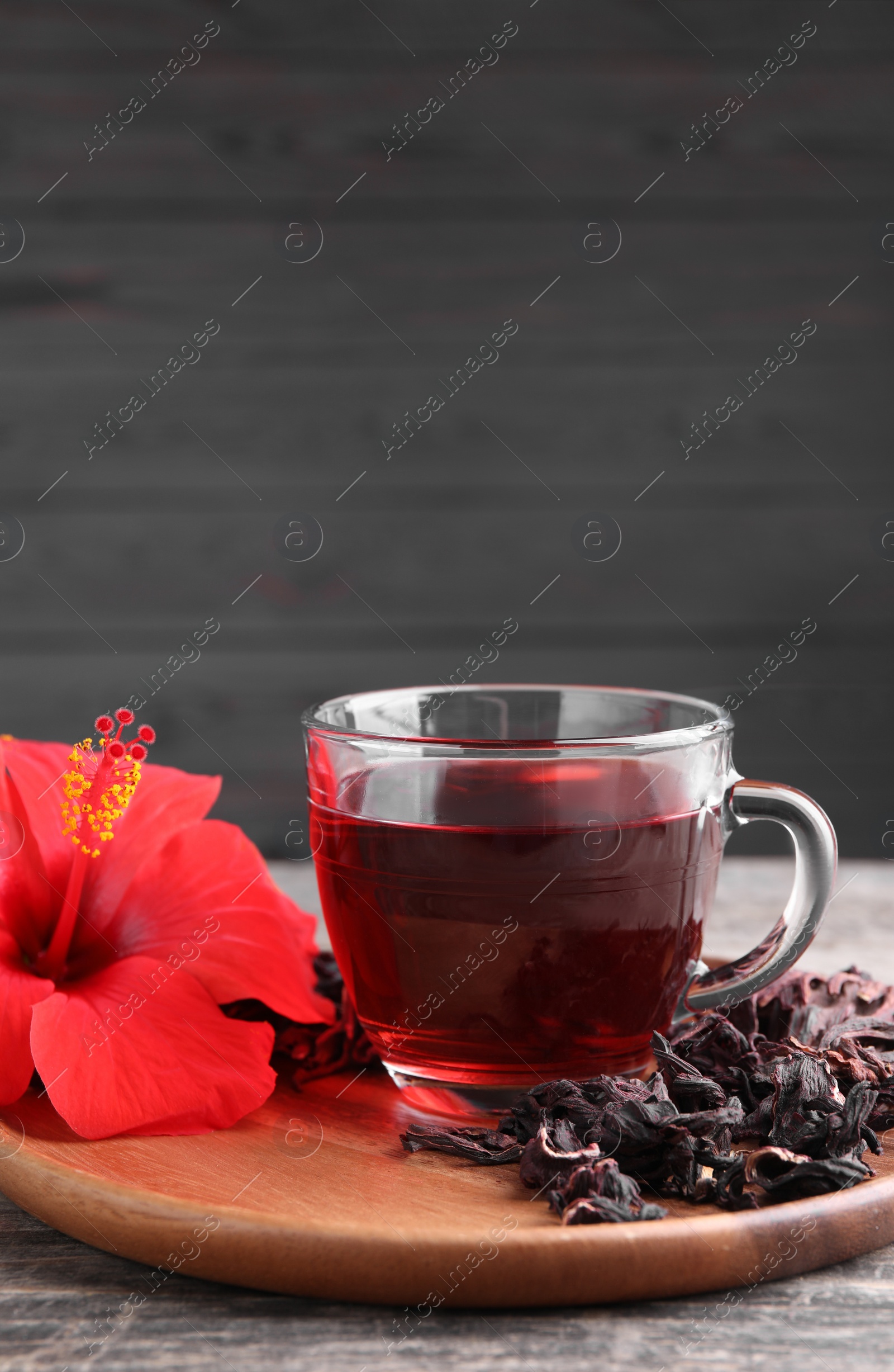 Photo of Delicious hibiscus tea and flowers on wooden table, space for text