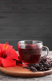 Delicious hibiscus tea and flowers on wooden table, space for text