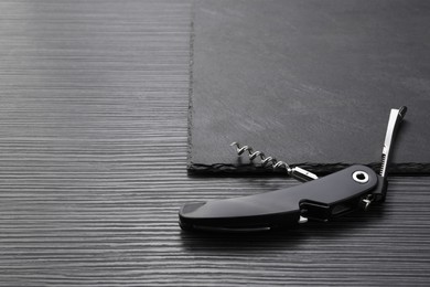 One corkscrew (sommelier knife) on black wooden table. Space for text