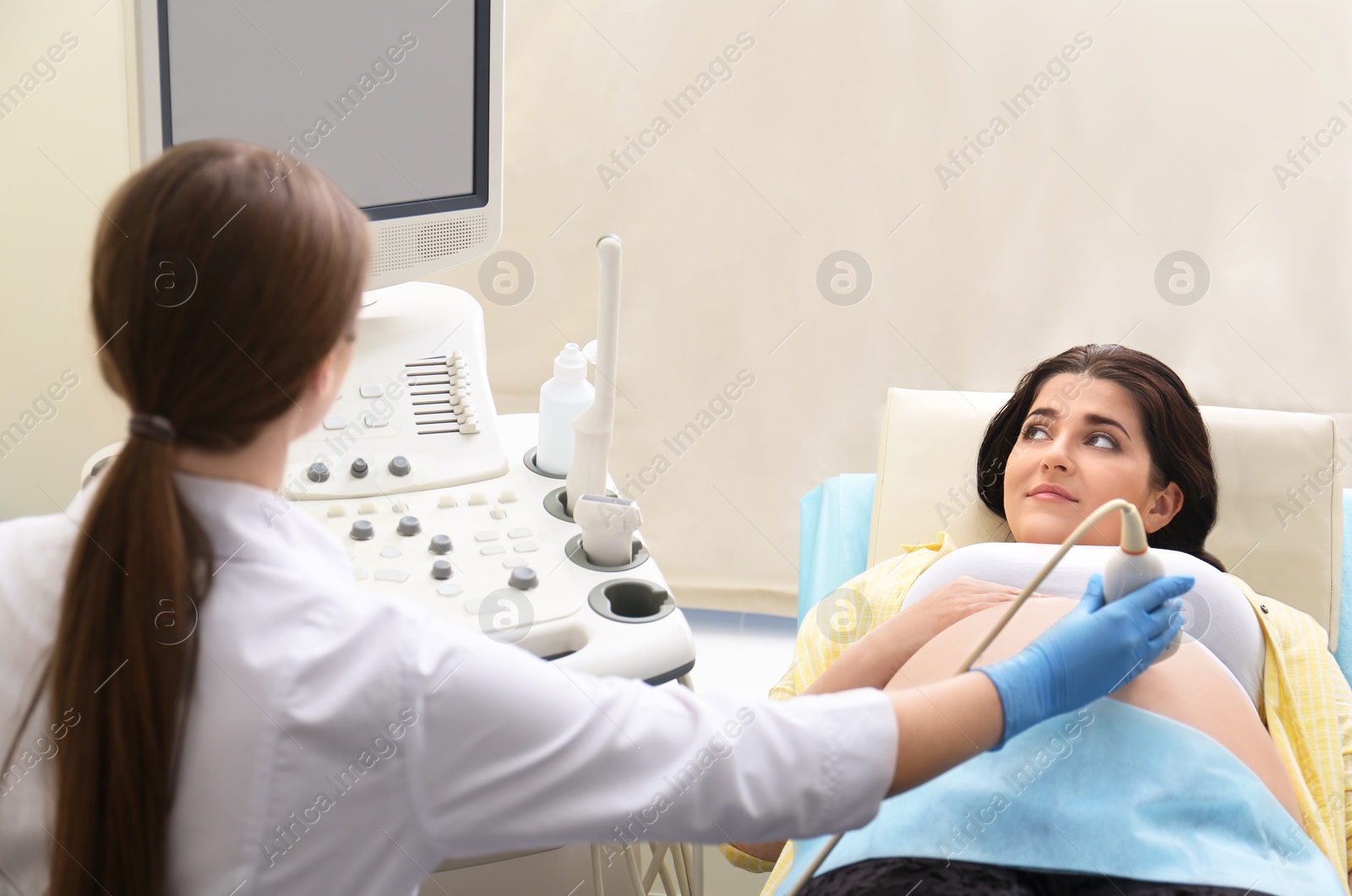 Photo of Young pregnant woman undergoing ultrasound scan in clinic