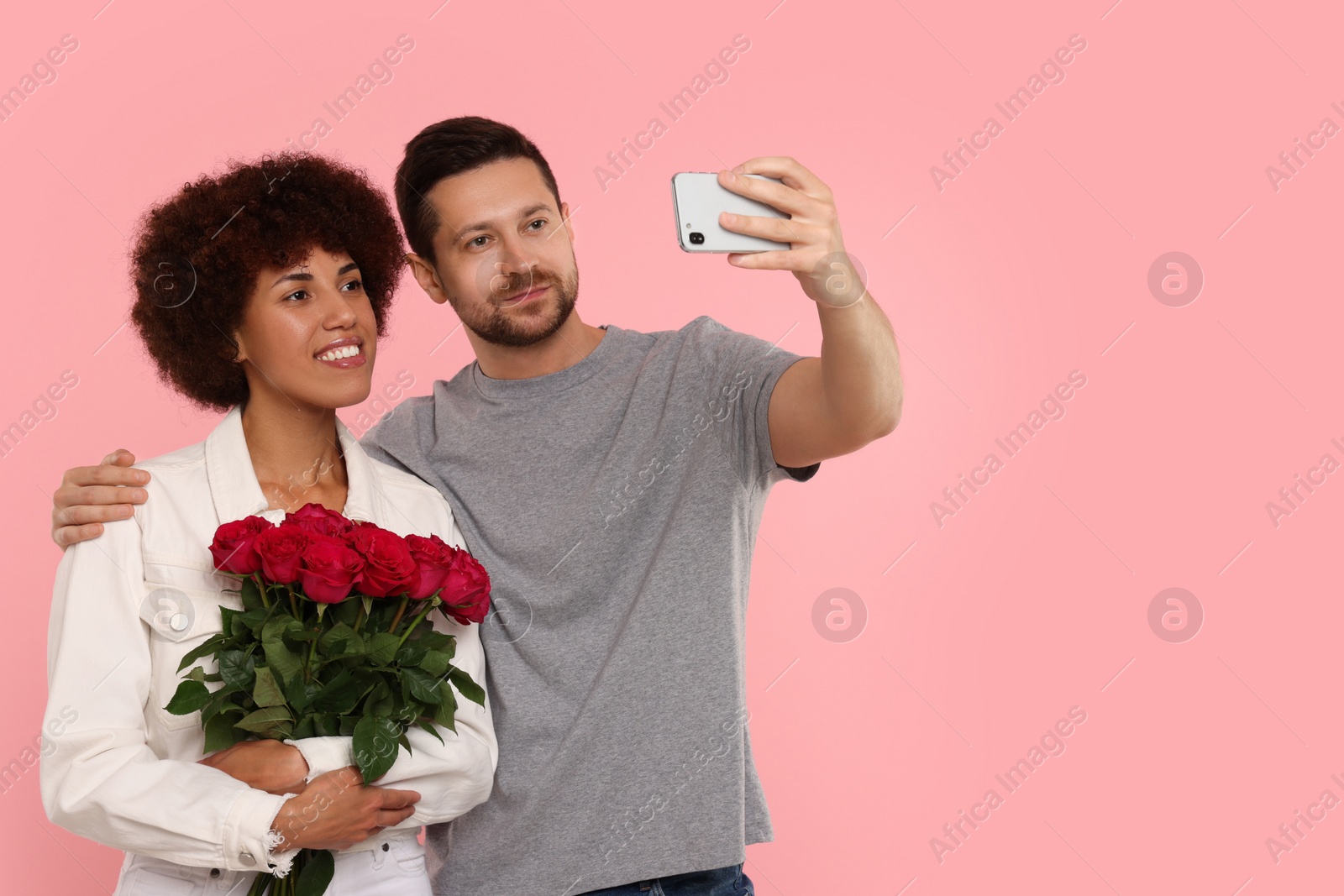 Photo of International dating. Happy couple taking selfie on pink background. Space for text