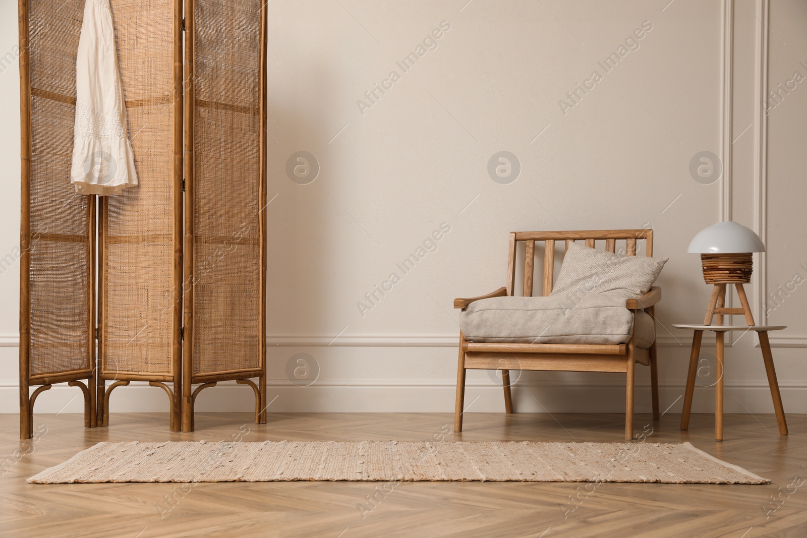 Photo of Stylish room with folding screen and armchair. Interior design