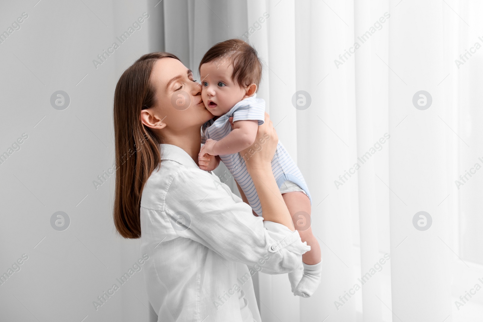 Photo of Happy mother kissing her little baby at home