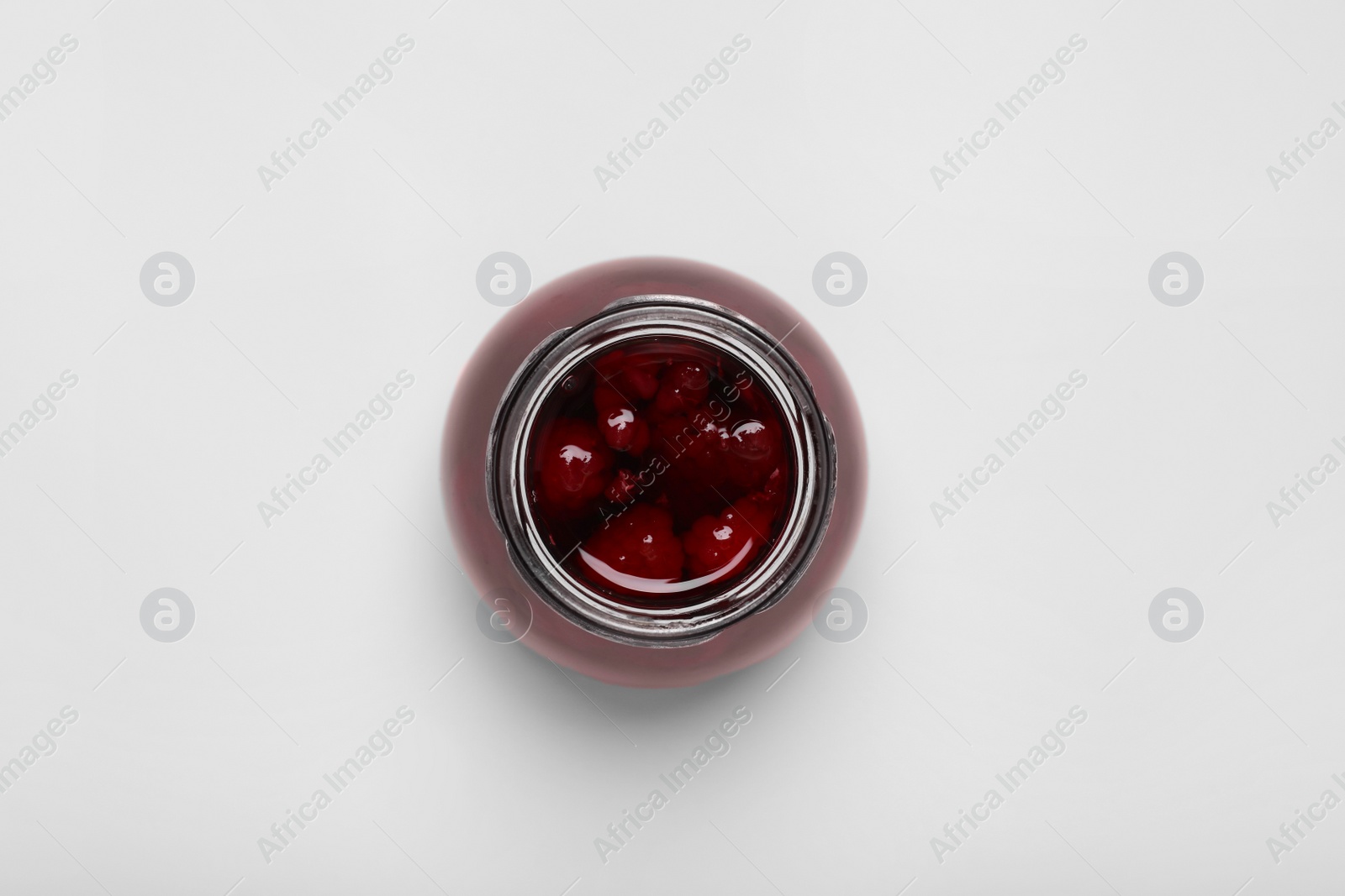 Photo of Tasty canned raspberry jam on white background, top view