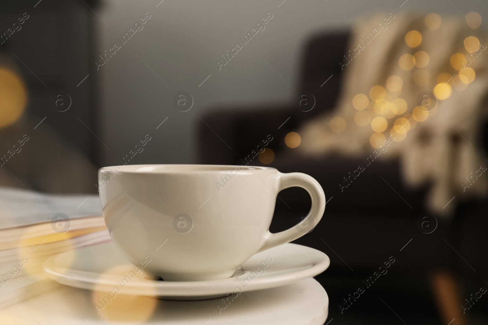 Photo of Cup with drink and stack of magazines on white table in living room, space for text