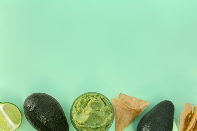 Delicious guacamole, avocados, lime and nachos on light background, flat lay. Space for text