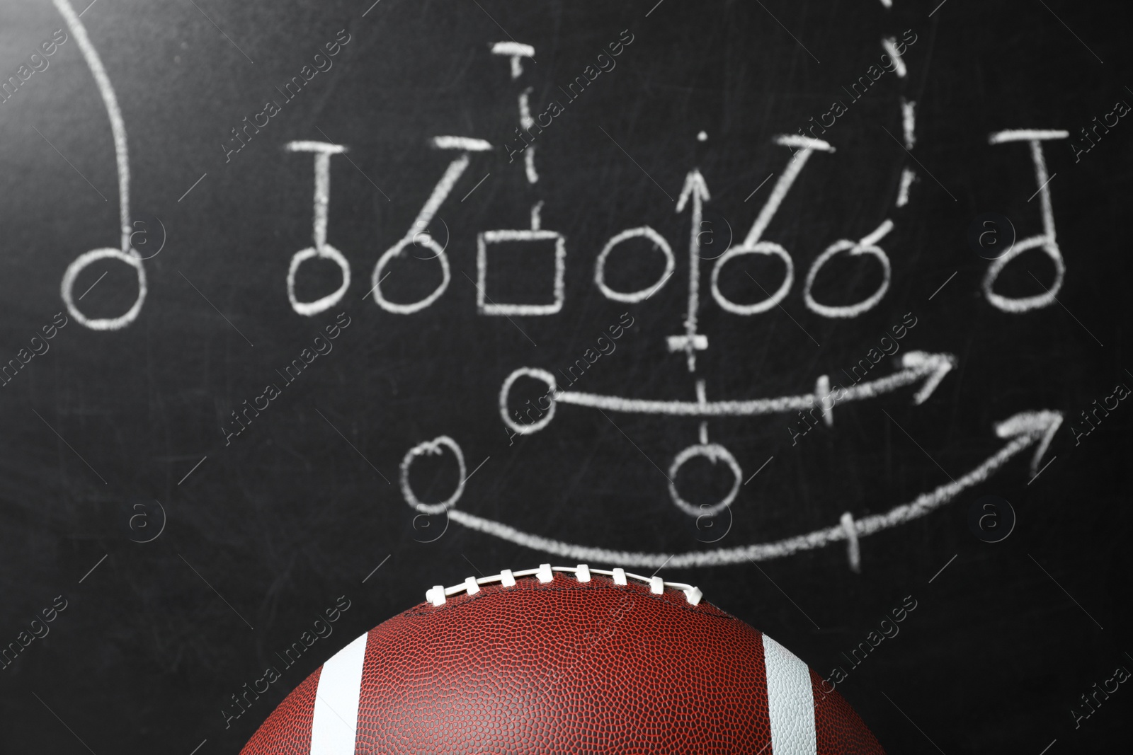 Photo of Leather American football on chalkboard with scheme of game, closeup