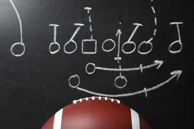 Leather American football on chalkboard with scheme of game, closeup