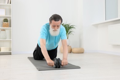 Photo of Senior man exercising with abdominal wheel at home. Sports equipment