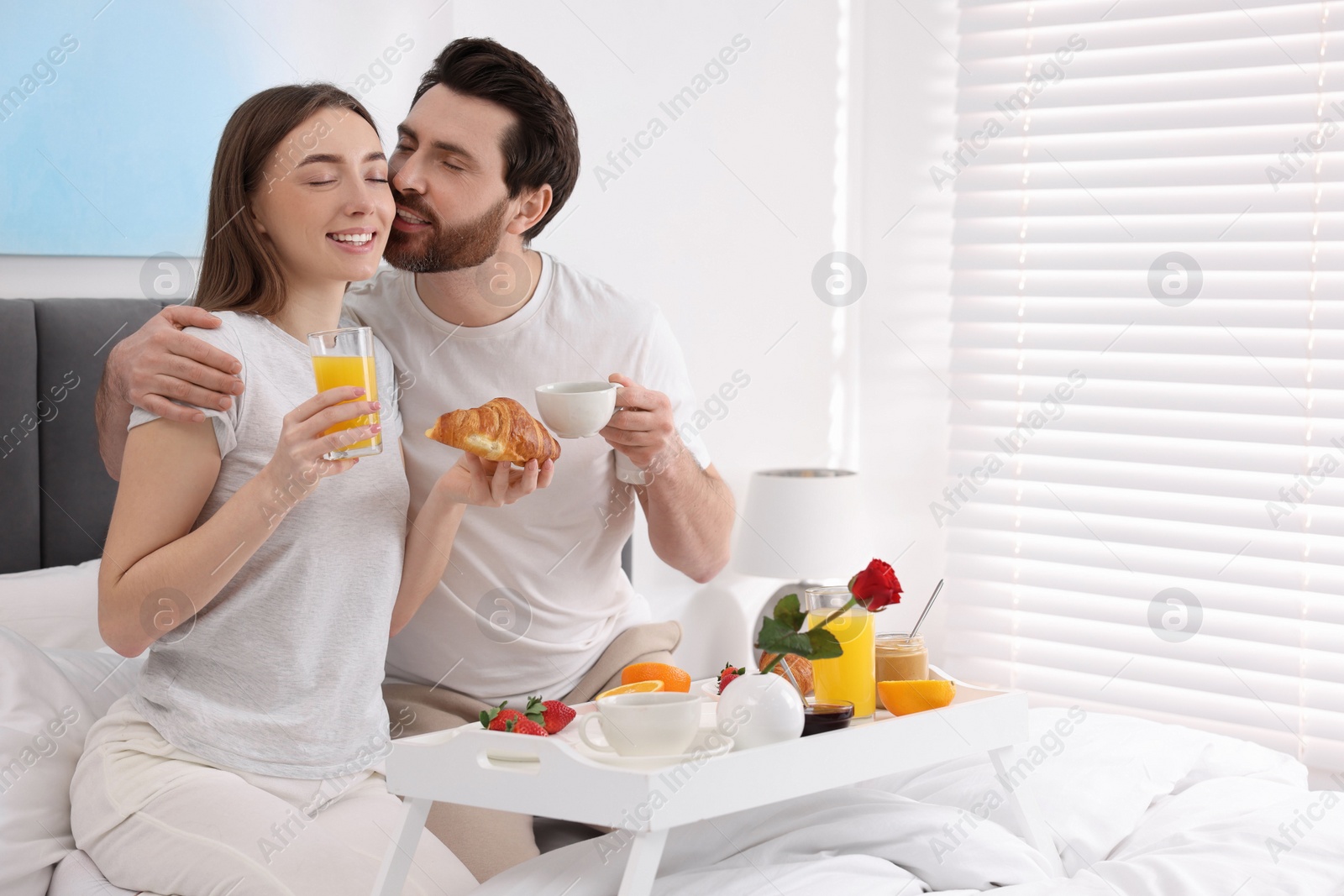 Photo of Lovely couple having breakfast in bedroom. Space for text