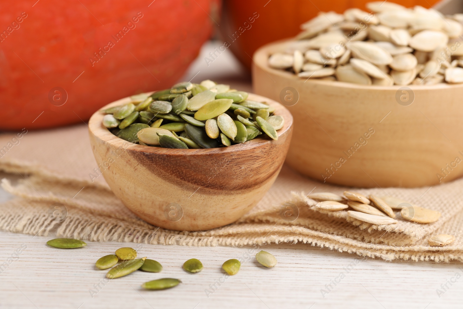 Photo of Bowls with pumpkin seeds on light wooden table